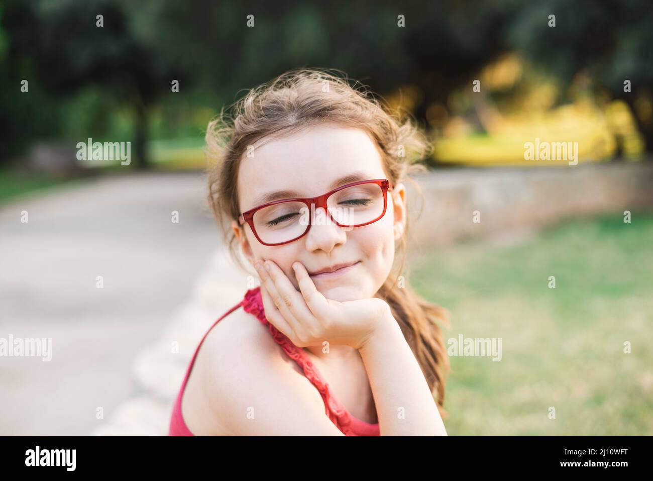 Ritratto di una ragazza sorridente con occhiali, occhi chiusi Foto Stock