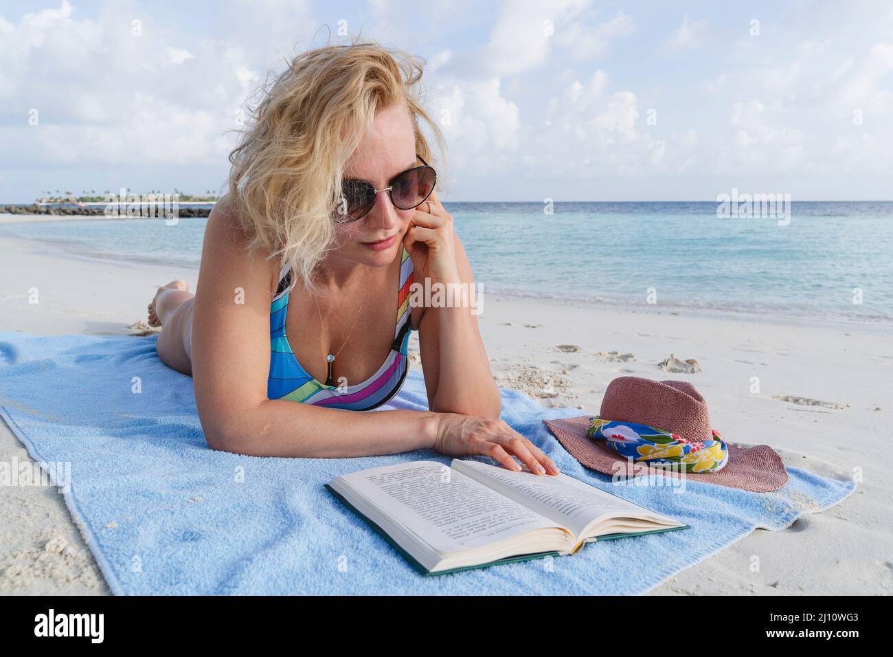 Una donna sta leggendo un libro sulla spiaggia. Foto Stock