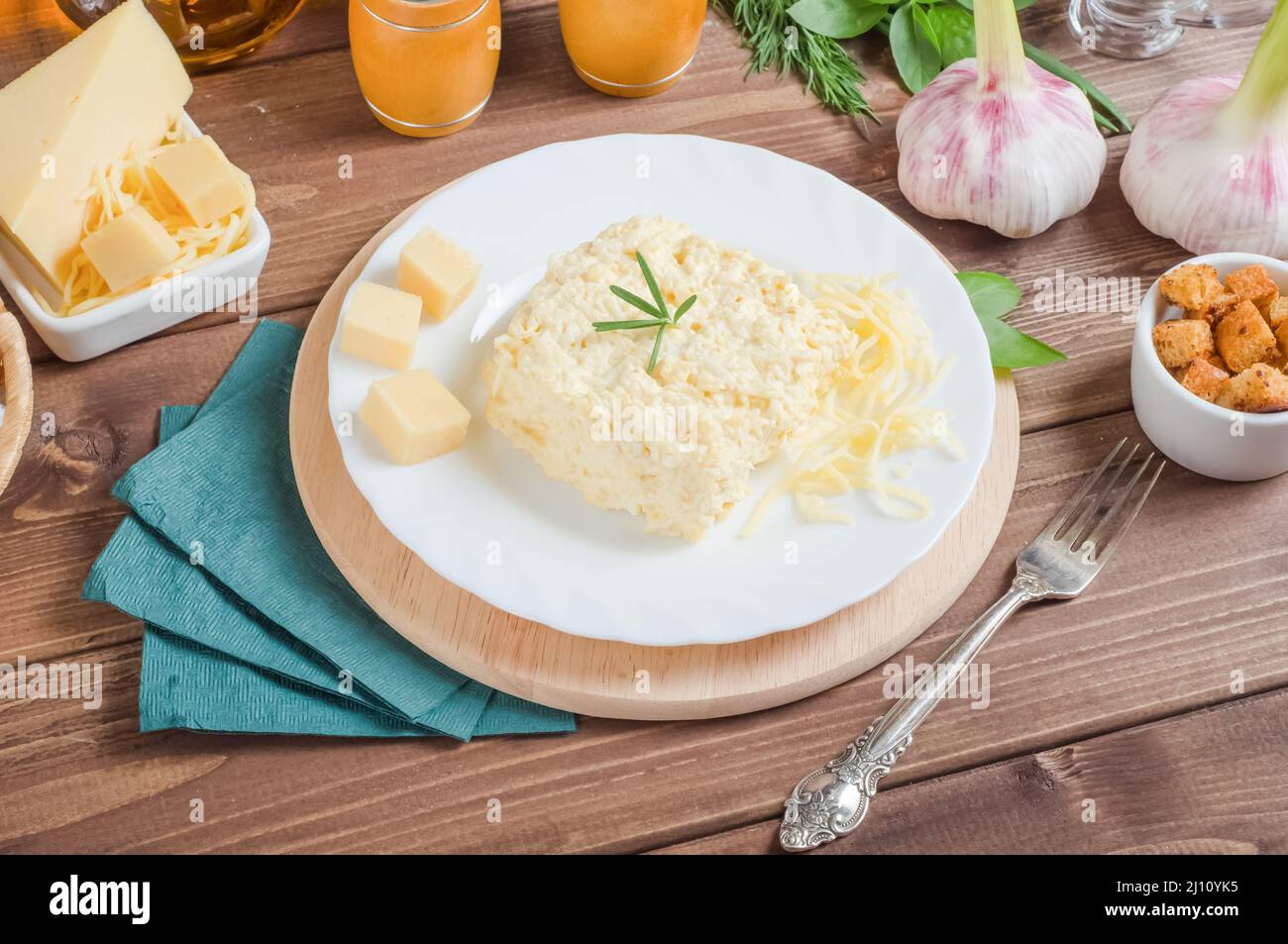 Tradizionale antipasto di formaggio morbido con aglio e maionese su un piatto bianco su sfondo di legno. Foto Stock