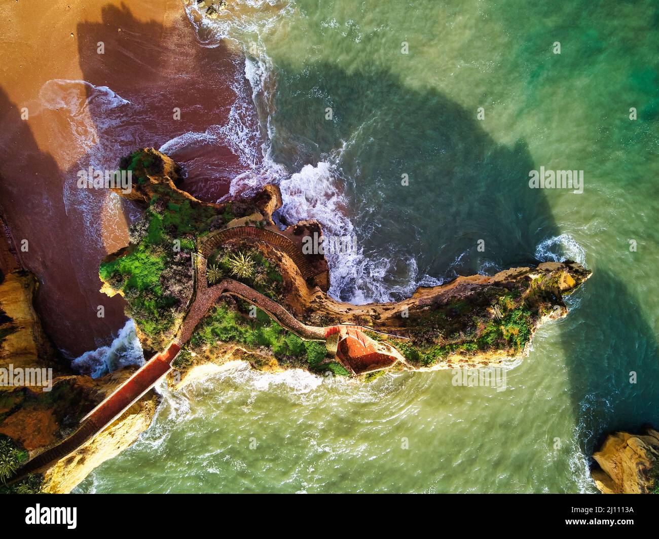 Foto aeree Praia dos Estudiantes o Spiaggia di studenti con gruppo di formazioni rocciose scogliere gialle-dorate lungo la costa calcarea, la città di Lagos Foto Stock