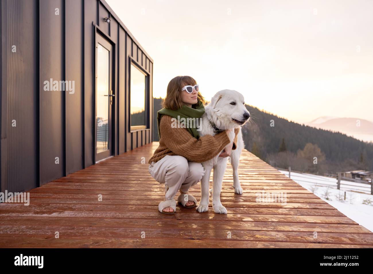 Donna con il suo cane che riposa sulla terrazza di una piccola casa sulla natura Foto Stock