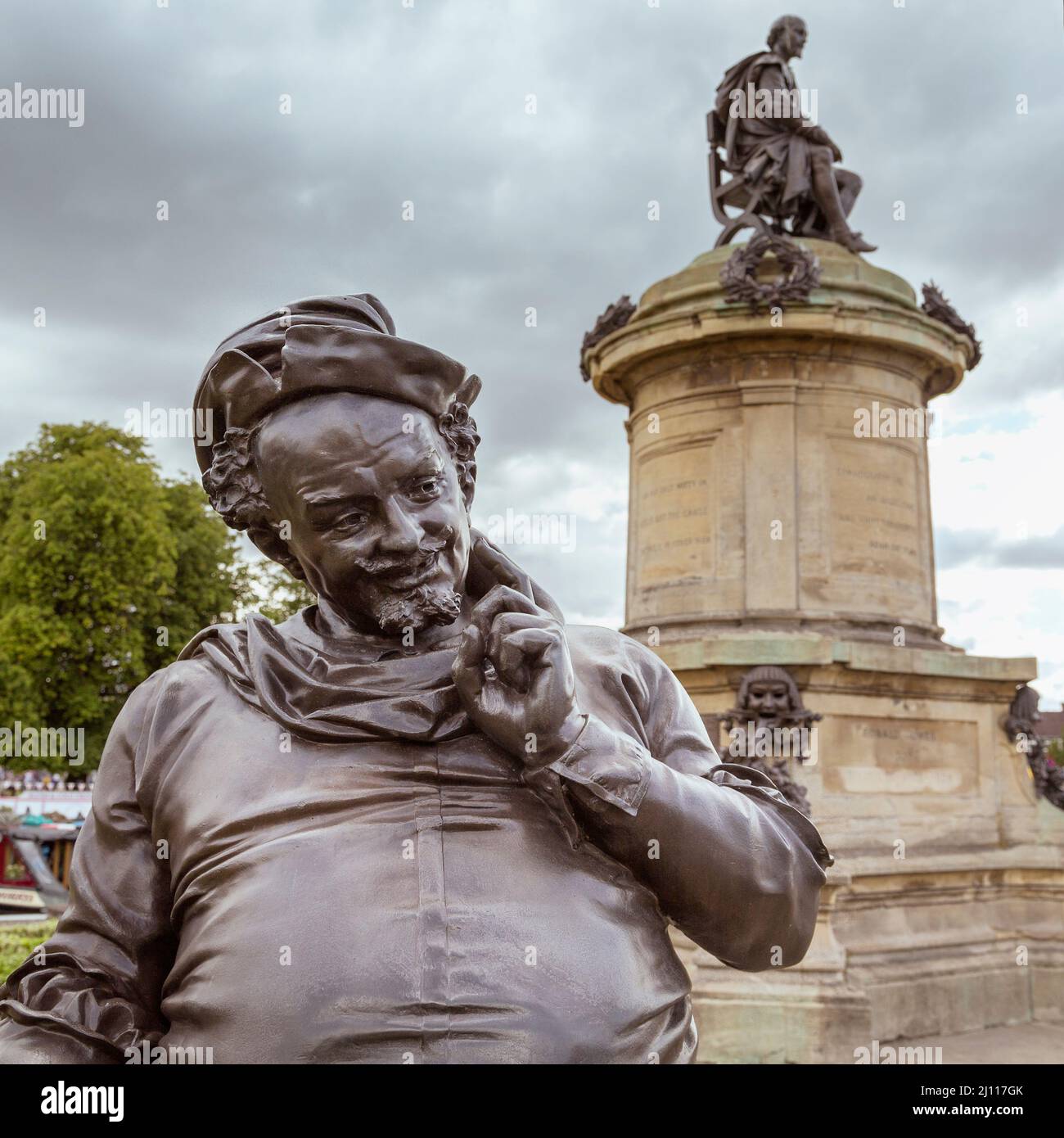 Una statua grinnesca del personaggio comico di William Shakespeare Falstaff si erge davanti a una statua del Bard stesso al monumento Gower, Stratford, Regno Unito. Foto Stock