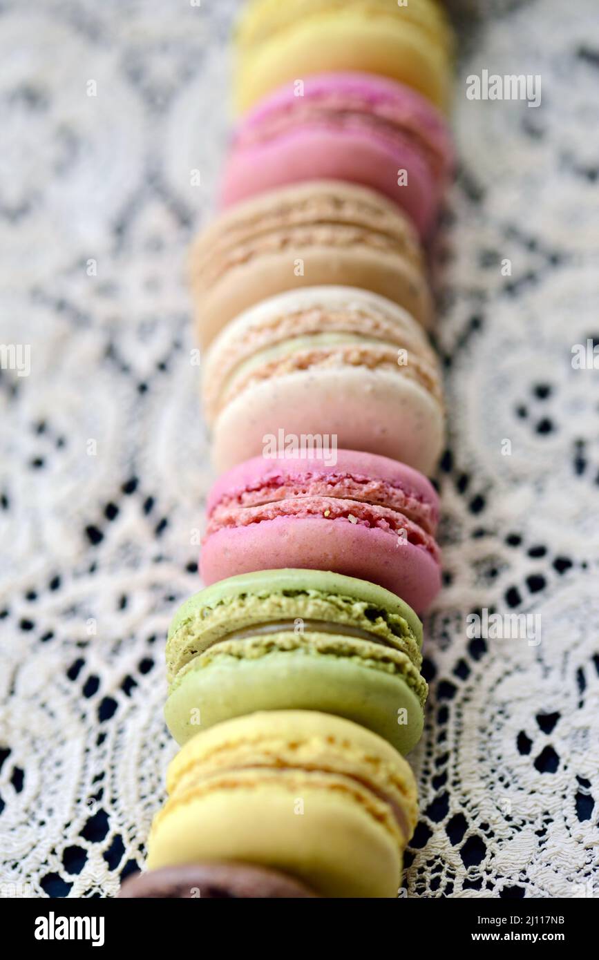 Una fila di colorati biscotti di macaron francese pastello su una tovaglia di pizzo d'epoca Foto Stock Una fila di colorati biscotti di macaron francese pastello su una tovaglia di pizzo d'epoca Foto Stock