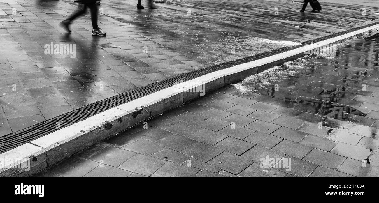 Pedoni che camminano sulla strada bagnata dalla pioggia a Bruxelles Foto Stock