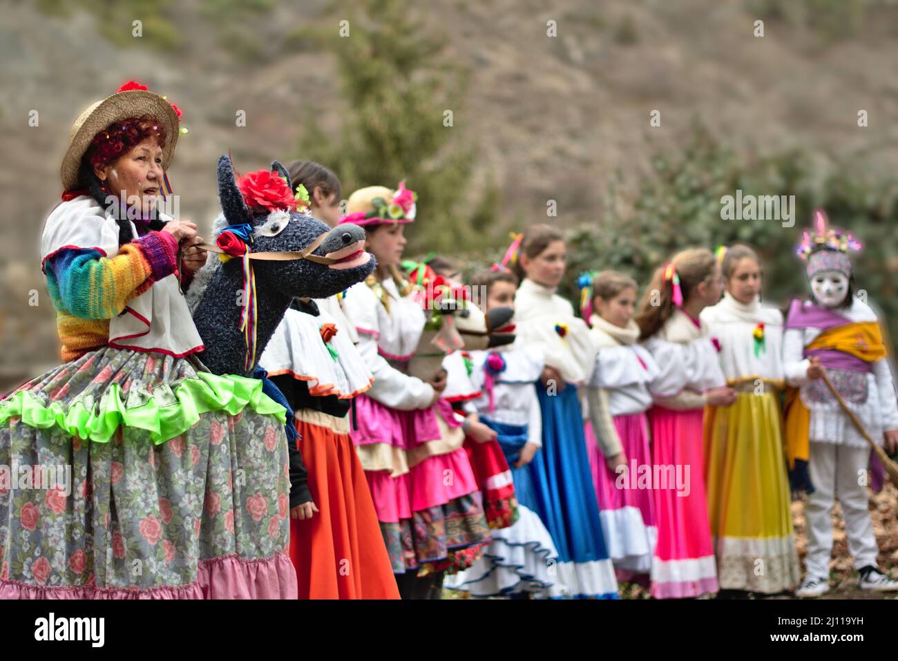 Enciso, Spagna – 5 marzo 2022: Donna anziana a sinistra travestita in un abito colorato che tiene le cinghie di un asino. In un gruppo di ragazze di fila in colo Foto Stock