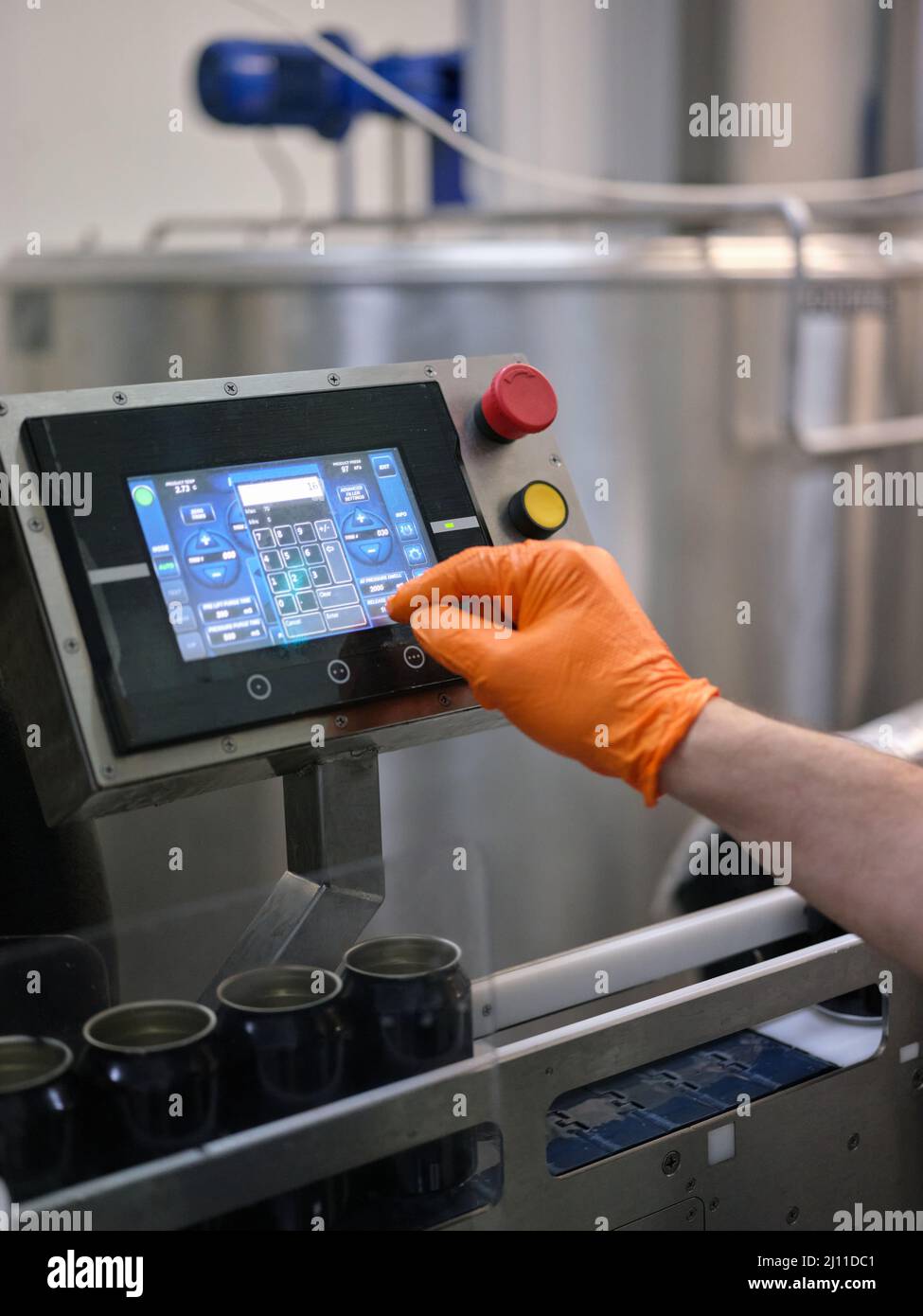 Uomo che lavora con una macchina per il riempimento elettronico della birra in un birrificio Foto Stock