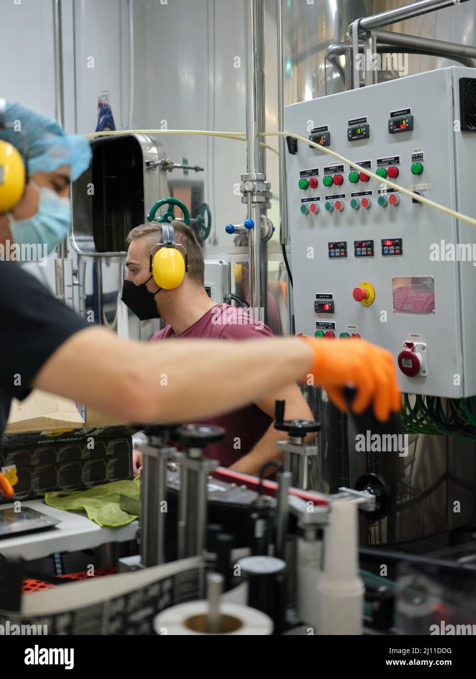 I lavoratori hanno covid maschera che lavora in una fabbrica artigianale di imballaggio birra Foto Stock