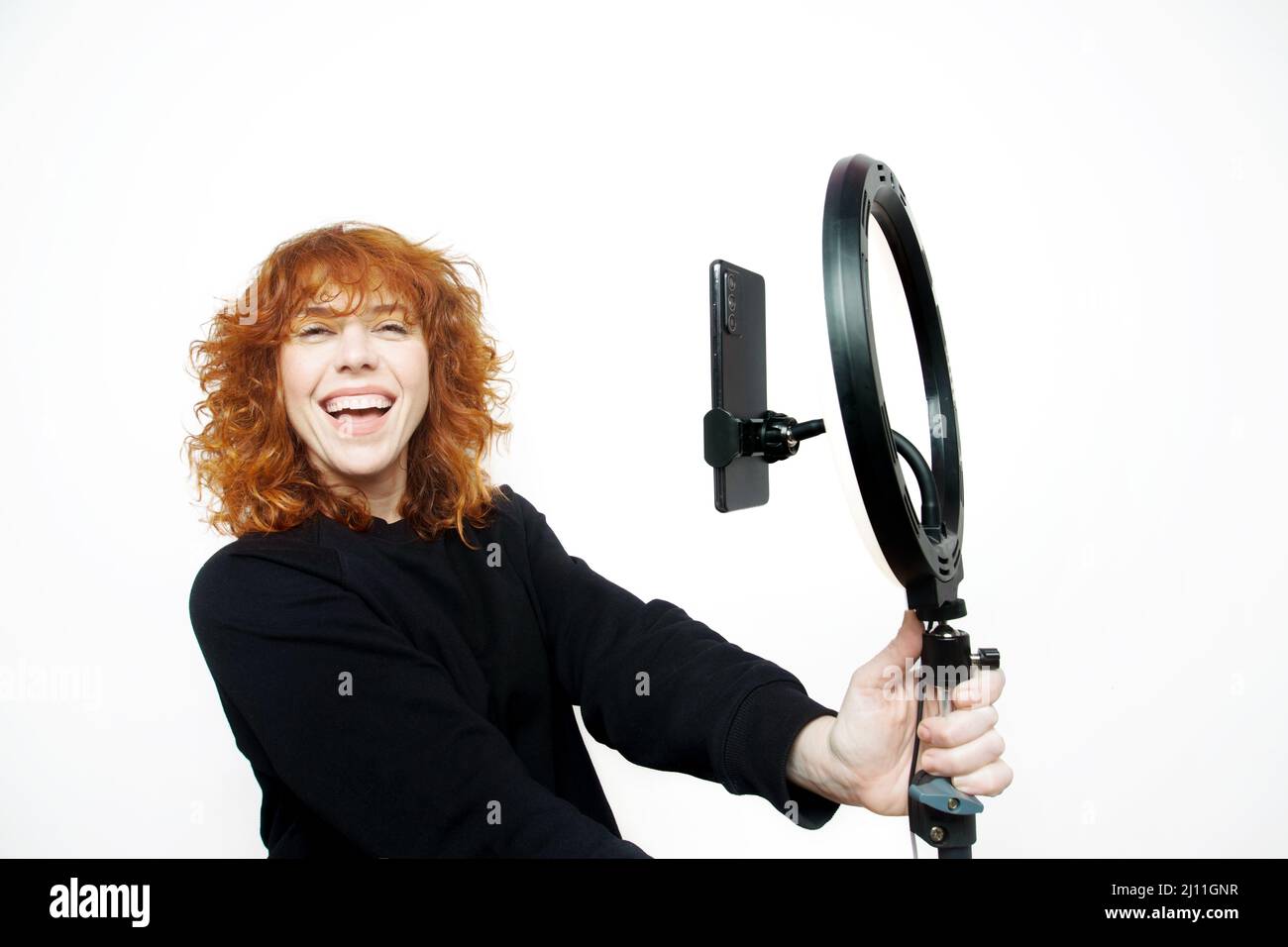 ragazza ricurly con capelli rossi che guarda la macchina fotografica con il sorriso e la bocca aperta che tiene un cerchio chiaro Foto Stock