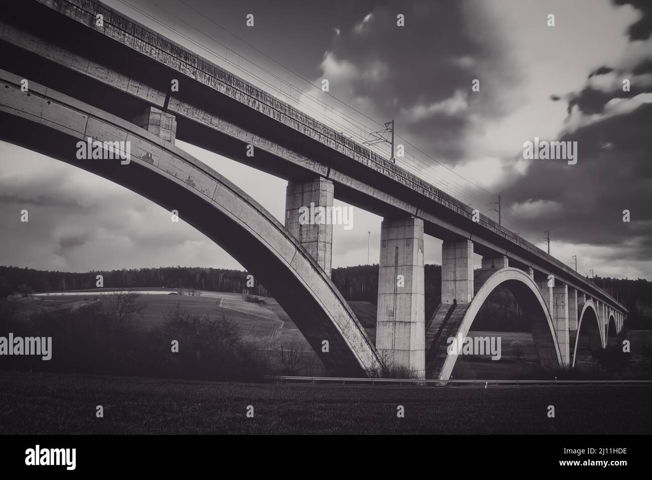 Ponte ferroviario espresso in cemento con archi e nuvole in movimento lunga esposizione Foto Stock