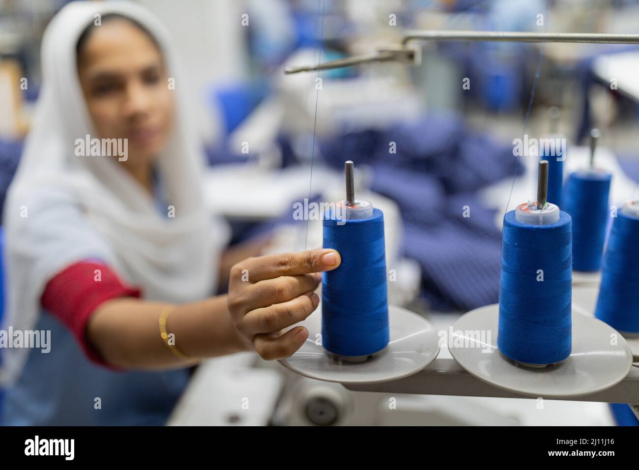 Una lavoratrice femminile sta prendendo filo da nastri per cucire vestiti in una fabbrica di abbigliamento readymade a Gazipur, Bangladesh. L'industria dell'abbigliamento pronto all'uso (RMG) è un pilastro di questa storia di successo economico. Il Bangladesh è oggi uno dei maggiori esportatori mondiali di abbigliamento, con il settore RMG che rappresenta il 84 per cento delle esportazioni del Bangladesh. Bangladesh. Foto Stock