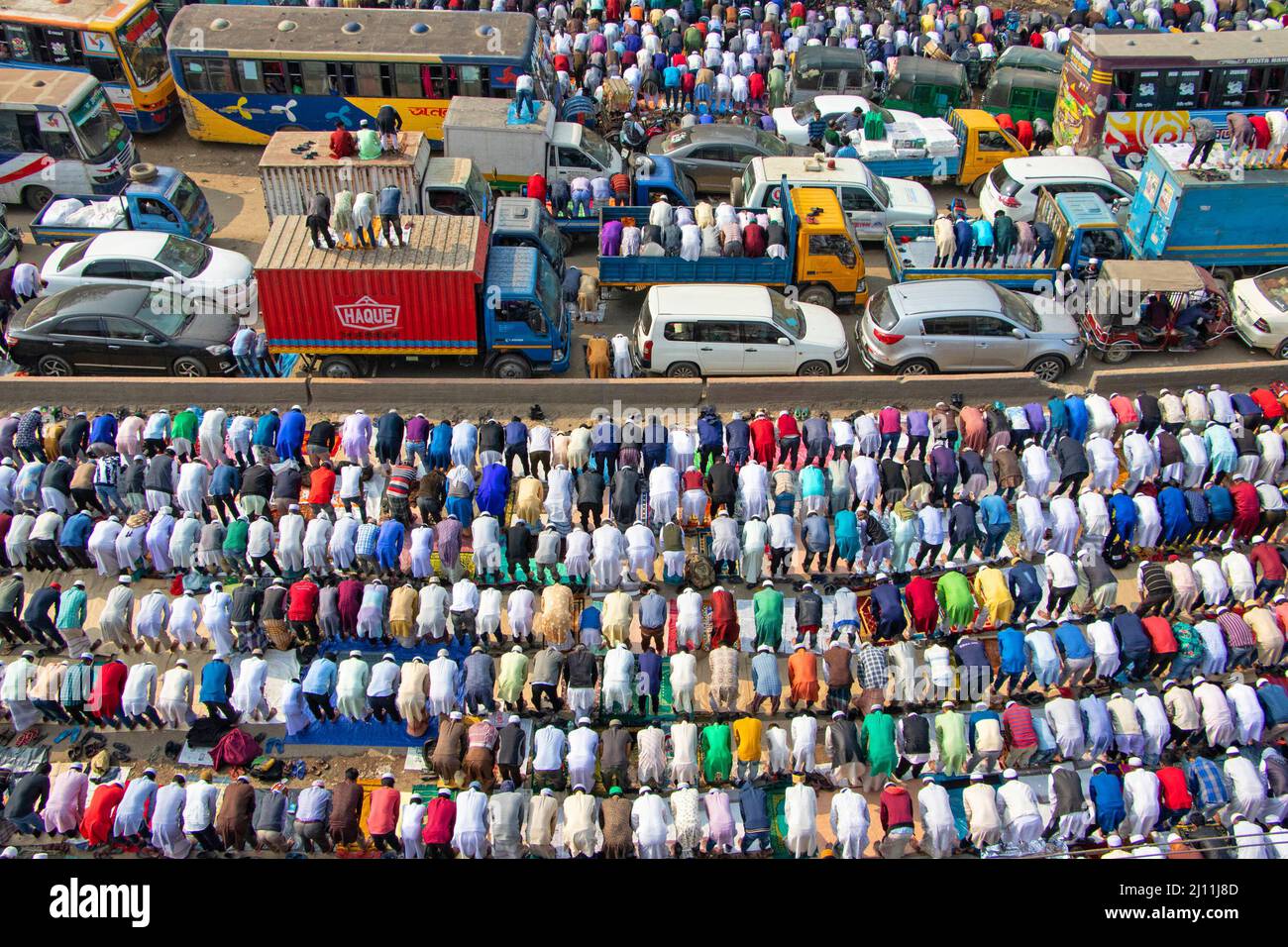 I devoti musulmani pregano nel bel mezzo di un incrocio stradale molto trafficato, causando un arresto del traffico, a Tongi, Dhaka, Bangladesh durante Bishwa Ijtema, uno dei maggiori raduni religiosi islamici osservati annualmente. Non bastano spazi di preghiera dedicati per gestire questo enorme numero di persone, così un gran numero di persone viene a Tongi, la strada principale di Dhaka. Tutti i trasporti a terra e i passaggi pedonali sono sospesi durante tale periodo. Bangladesh. Foto Stock