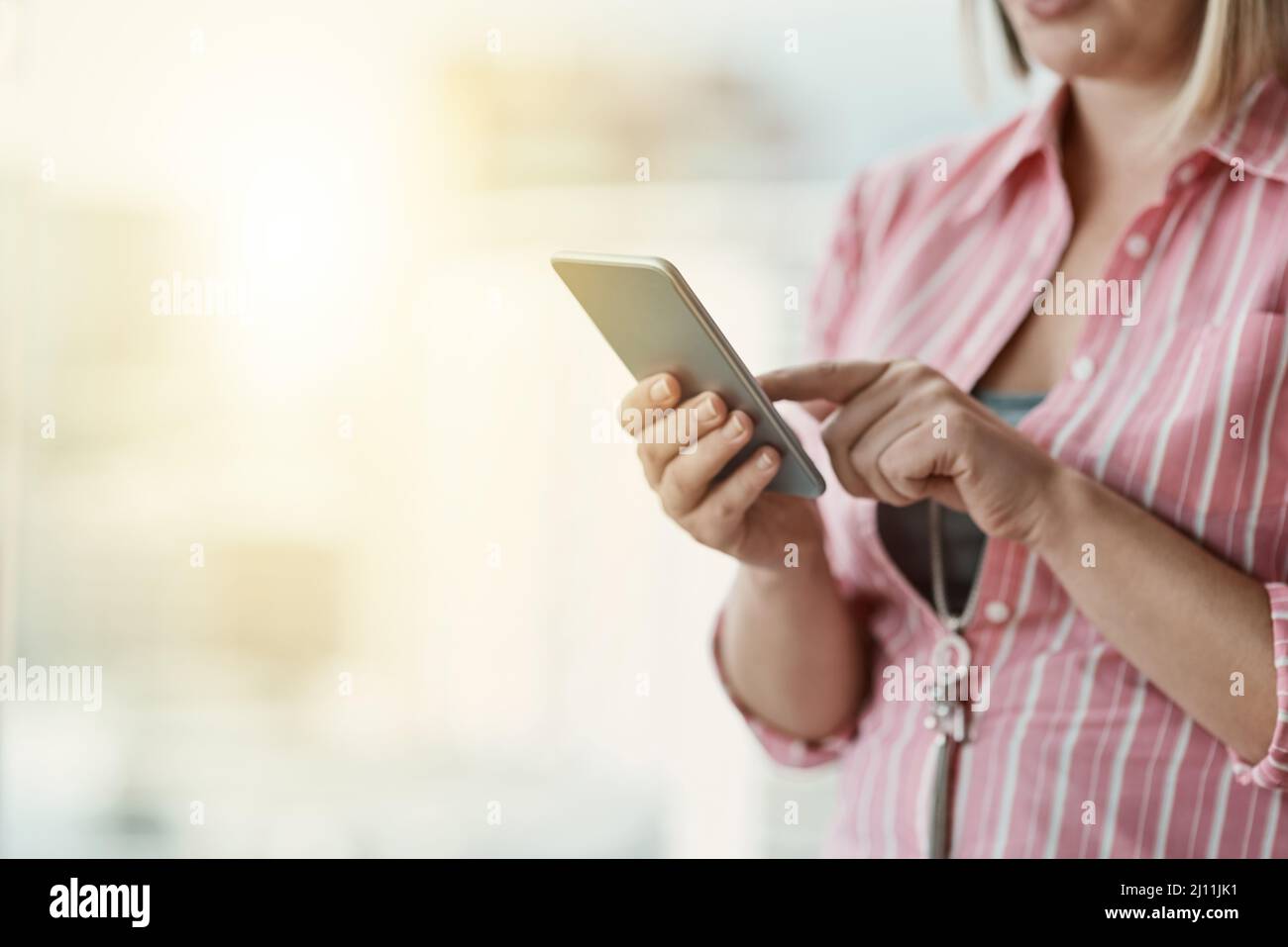 Rimanere connessi e in loop. Scatto corto di una donna d'affari non identificabile che usa un cellulare in un ufficio. Foto Stock