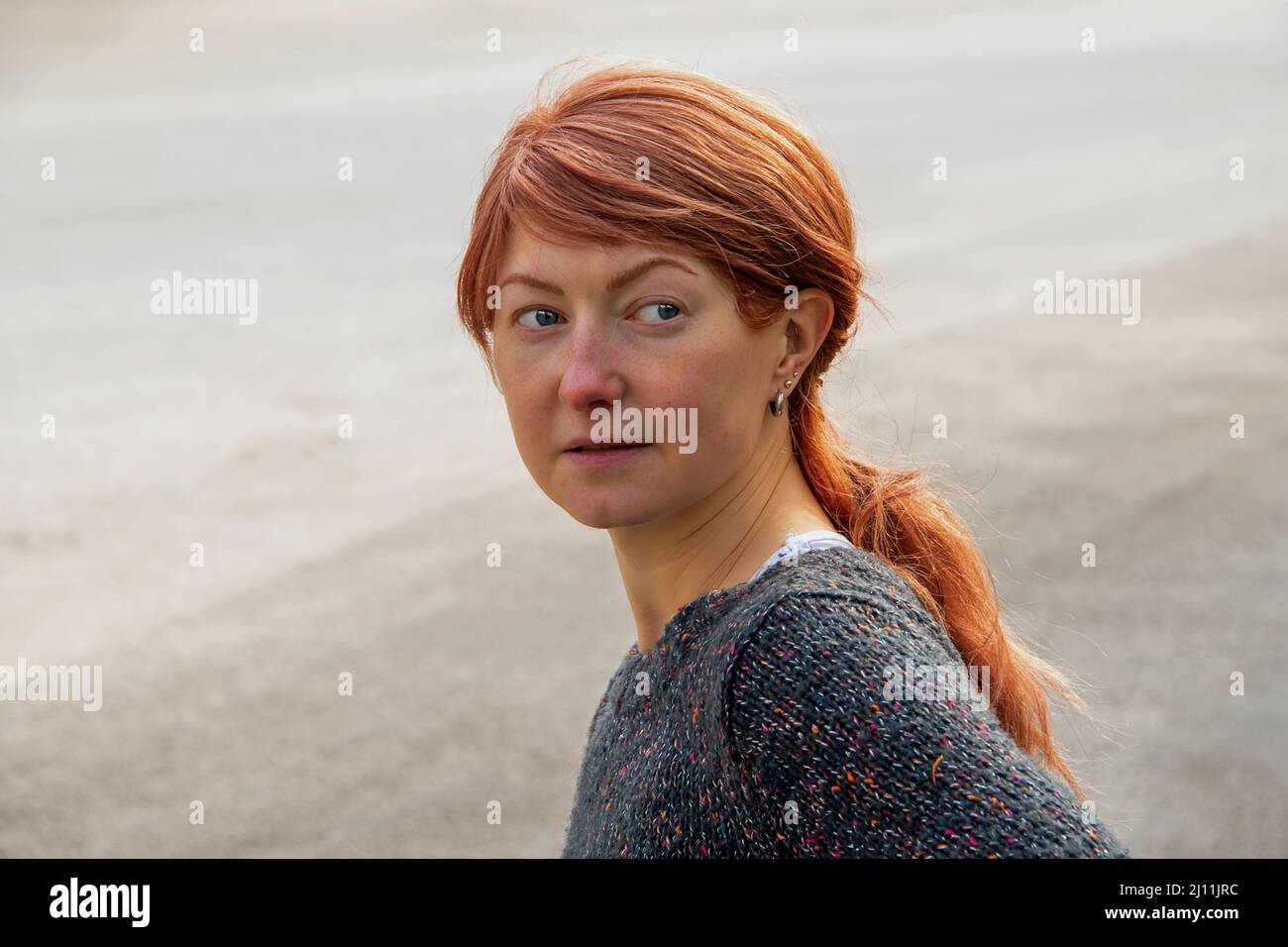 Ritratto di una donna europea dai capelli rossi con occhi blu che guardano via Foto Stock