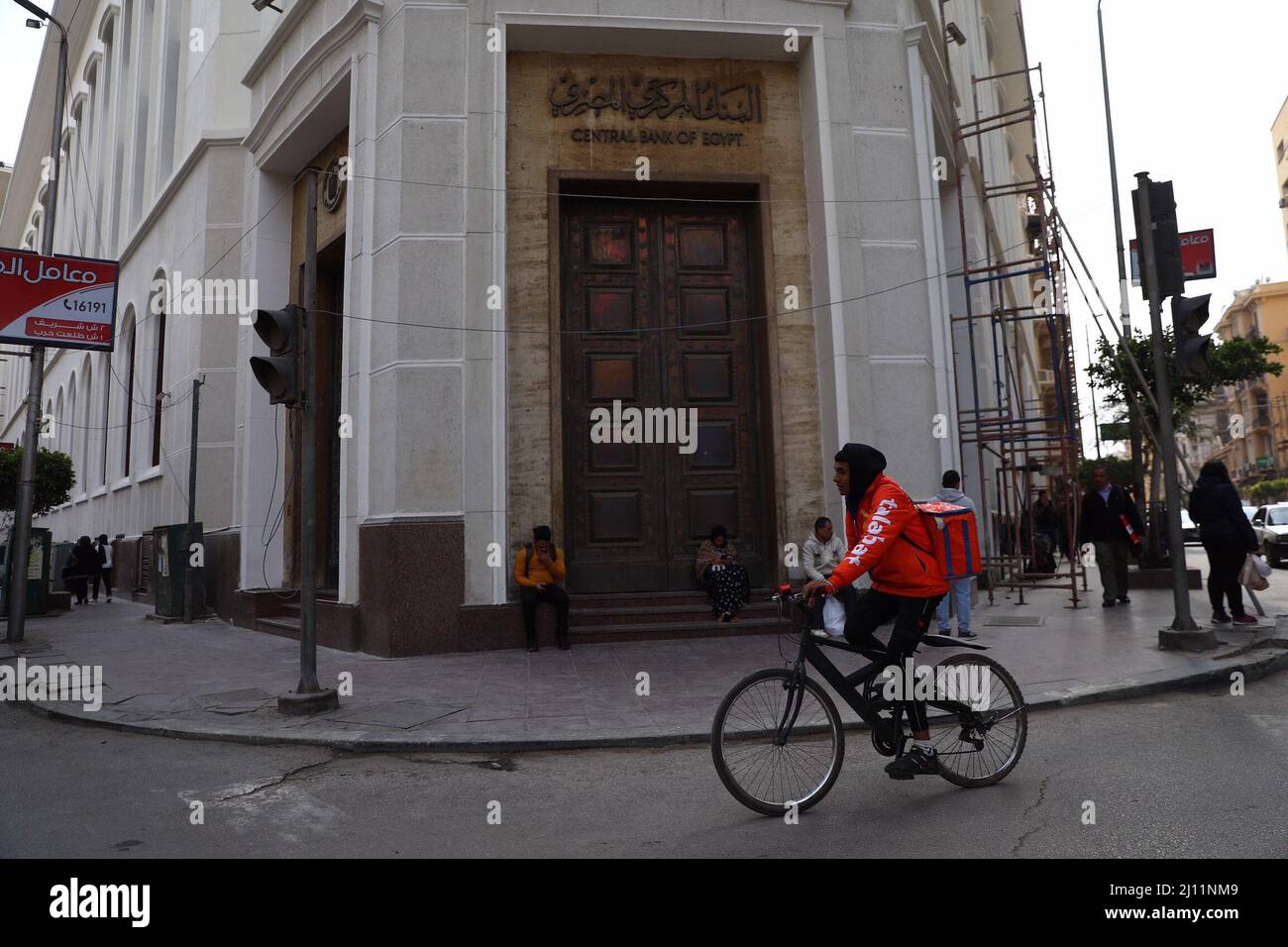 Cairo, Egitto. 21st Mar 2022. Un uomo biciclette dopo la costruzione della  Banca Centrale d'Egitto al Cairo, Egitto, il 21 marzo 2022. Lunedì il  governo egiziano ha introdotto nuove misure economiche per