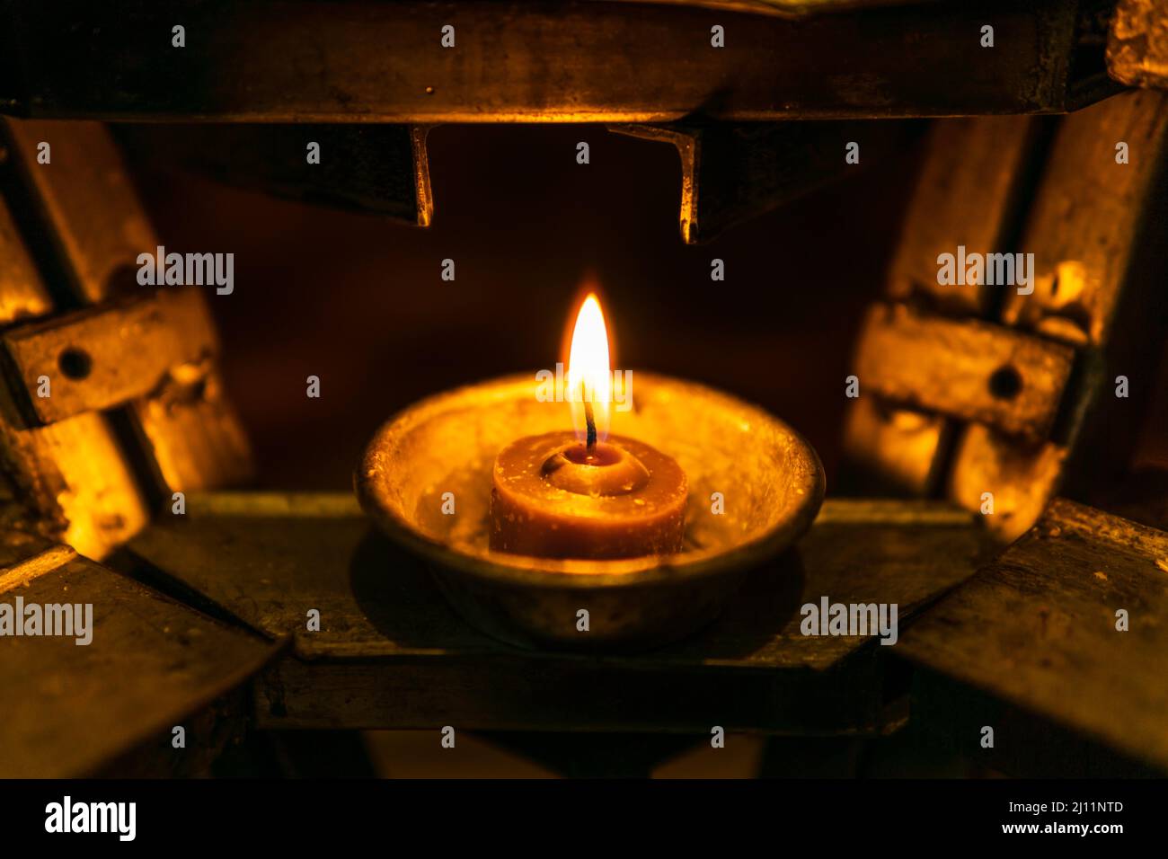 Una candela votiva illuminata su una rastrelliera votiva in una chiesa cattolica. Foto Stock