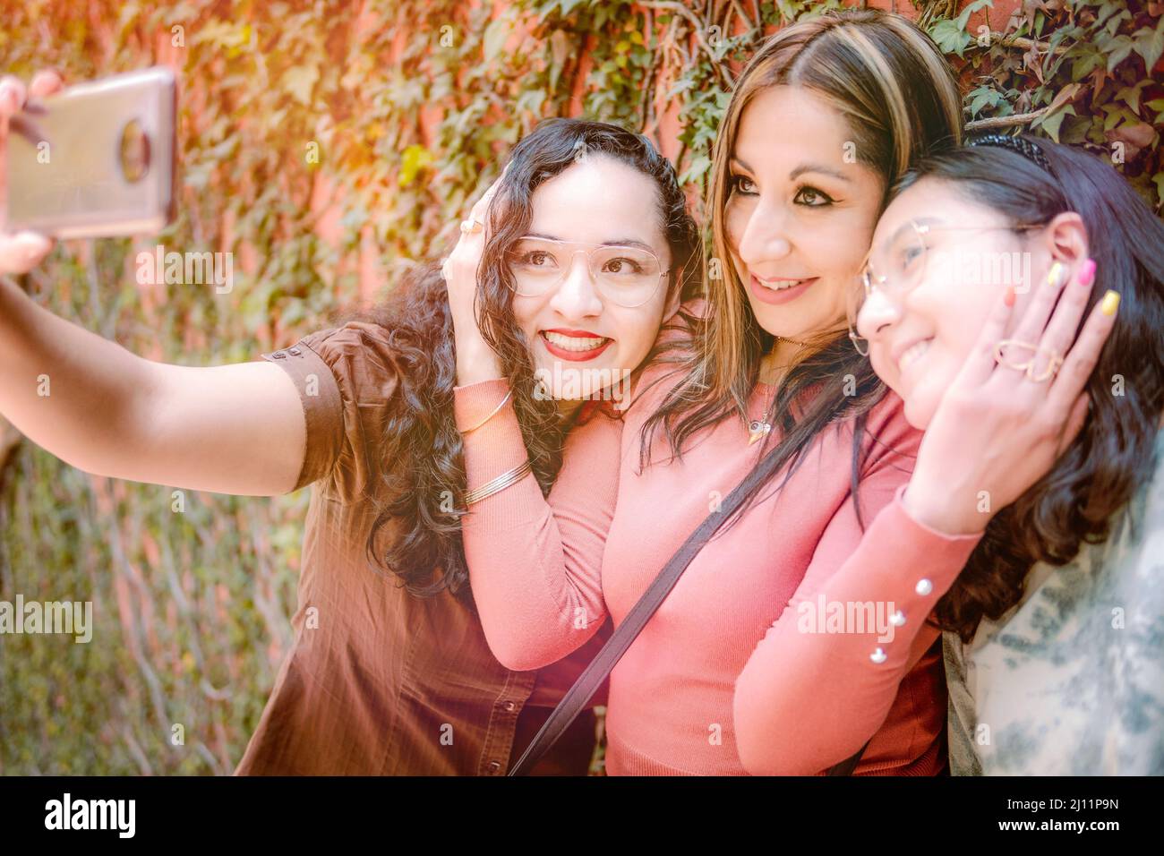 Tre ragazze che prendono selfie per strada, osservando felice perché si amano così tanto Foto Stock