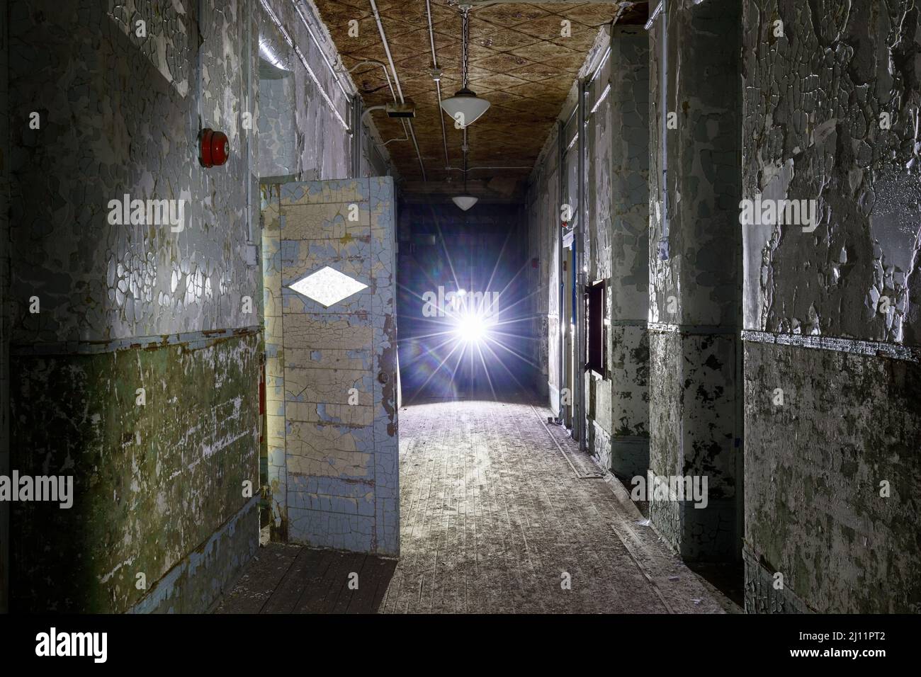 Corridoio all'interno di un asilo abbandonato con illuminazione soffusa. Foto Stock