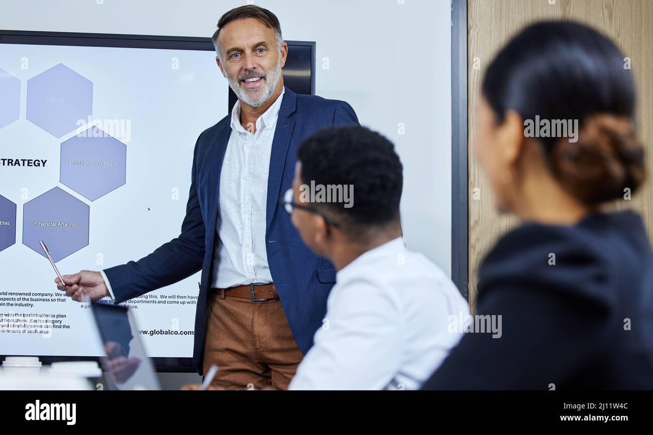 Approfondire l'analisi finanziaria. Scatto di un uomo d'affari maturo che fa una presentazione ai suoi colleghi in un ufficio. Foto Stock