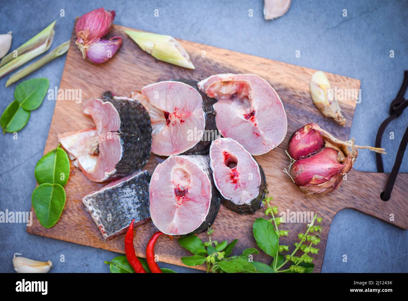 Pesce a strisce con testa di serpente tritato con ingredienti erbe e spezie su tagliere di legno e piano cottura sfondo, fresco crudo Snake testa di pesce menu f Foto Stock