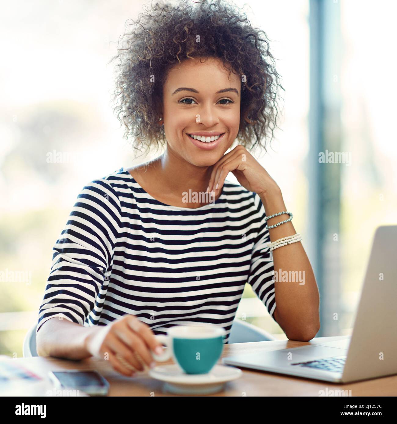 Il lavoro autonomo è la strada da percorrere. Ritratto di una giovane donna che beve un caffè mentre lavora su un computer portatile a casa. Foto Stock