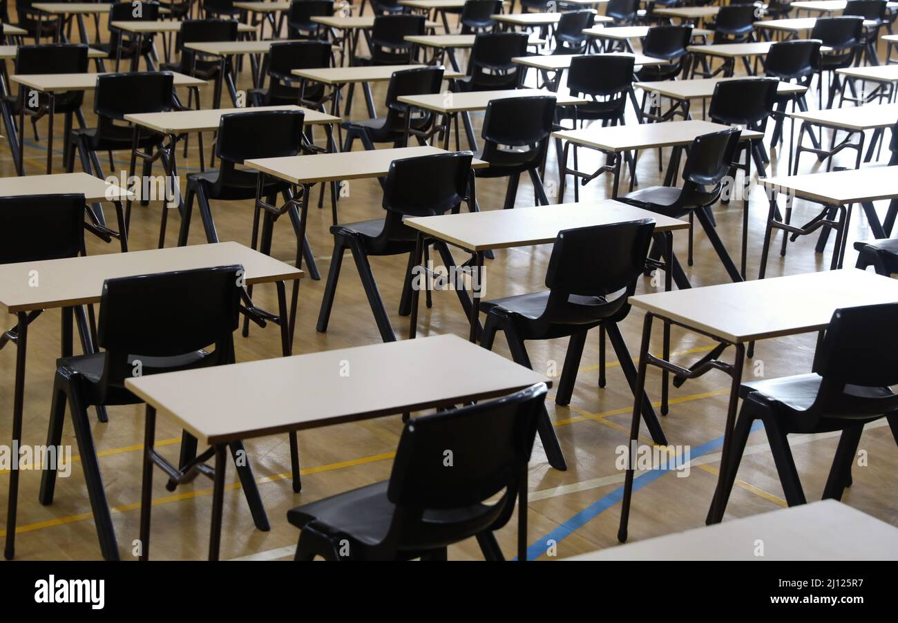 Righe o piano singolo studente scrivanie o tavoli disposti in ordine per esami o esami scolastici principali. Foto Stock
