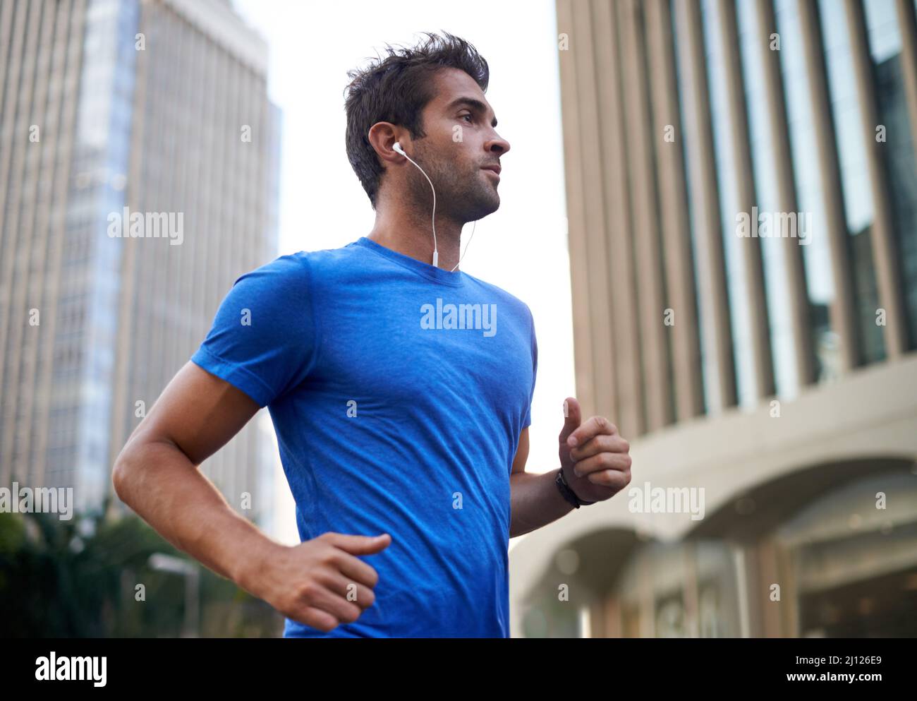 Corre lungo il suo percorso preferito della città. Scatto di un giovane che fa jogging attraverso la città. Foto Stock