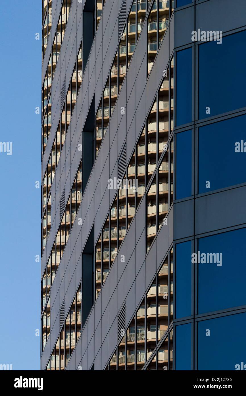 Un edificio di appartamenti che si riflette nelle finestre di una moderna torre di uffici. Kashimada, Kawasaki, Kanagawa, Giappone. Foto Stock