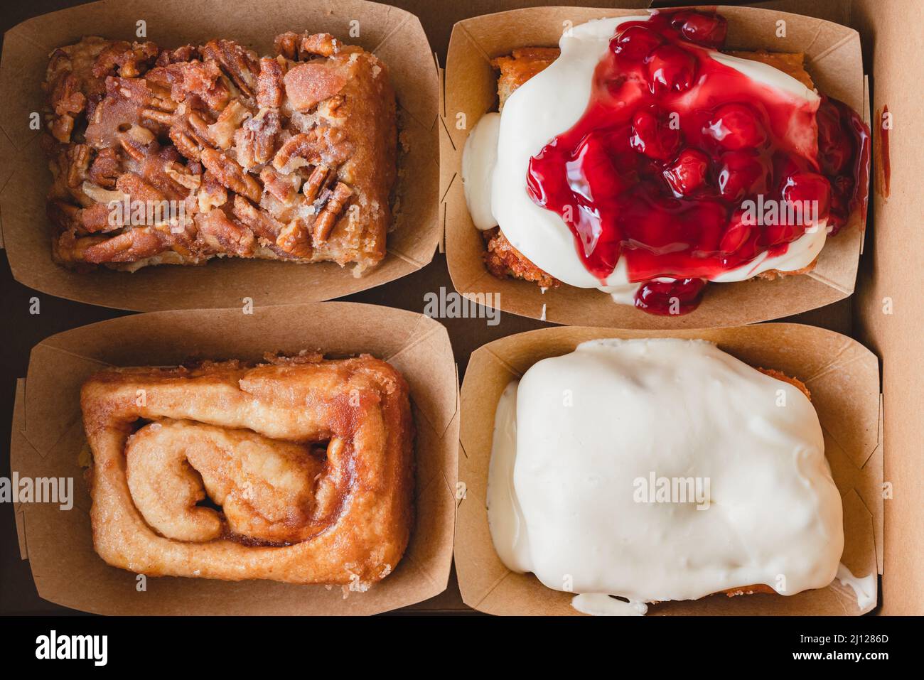 Pecan, formaggio cremoso glassato, glassato di ciliegia, e rotolini originali alla cannella in primo piano, posa piatta Foto Stock