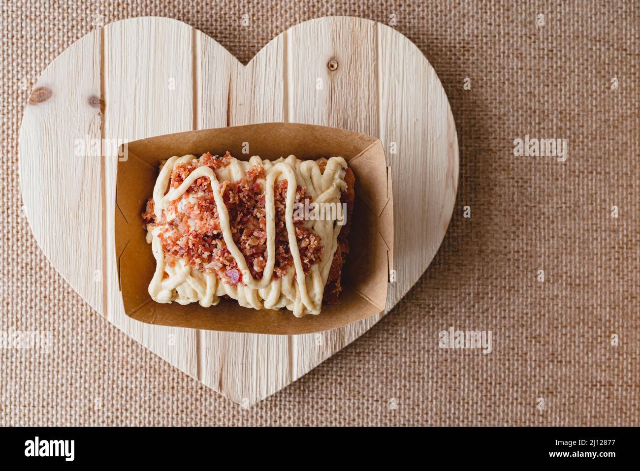 Rotolo di cannella di Maple Bacon da vicino su un asse a forma di cuore di legno, disposizione piatta con spazio copia Foto Stock