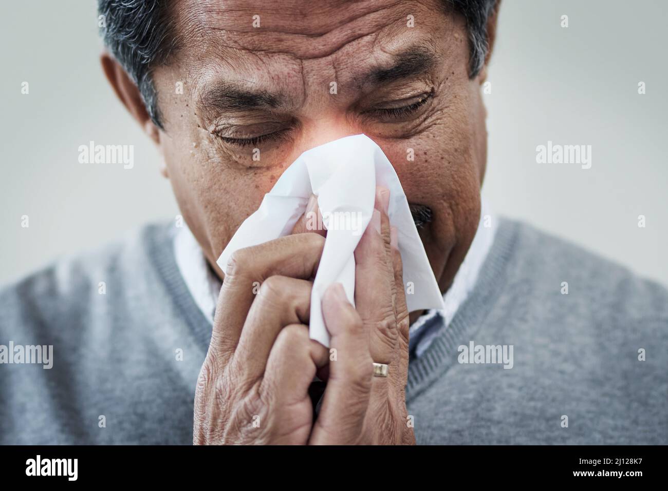 La stagione delle allergie è qui. Colpo di un uomo maturo che soffia il naso. Foto Stock