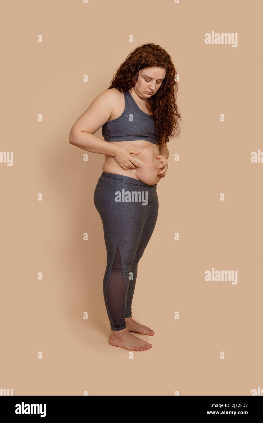 Foto verticale di grasso a piedi nudi peso extra donna doppio mento, guardando sul ventre penzolante. Foto Stock