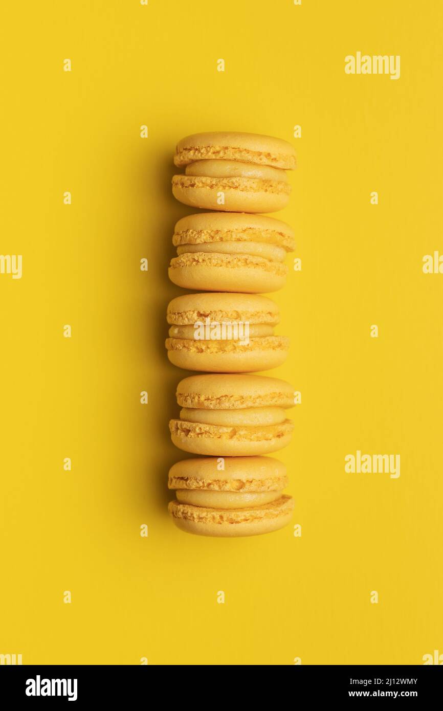 Amaretti gialli dolci. Macaroni francesi tradizionali. Gustoso dessert su sfondo giallo. Vista dall'alto. Foto Stock