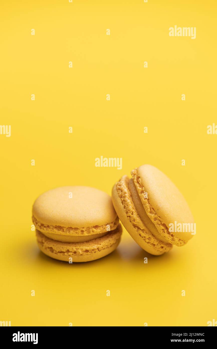 Amaretti gialli dolci. Macaroni francesi tradizionali. Gustoso dessert su sfondo giallo. Foto Stock