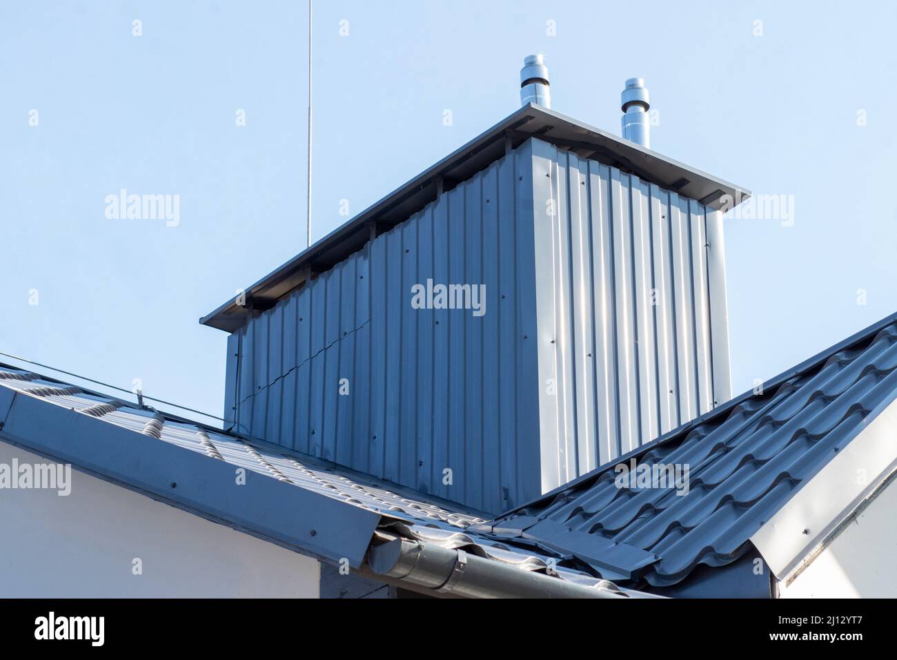 Sistema di ventilazione con camini e condotti sul tetto di un edificio residenziale Foto Stock