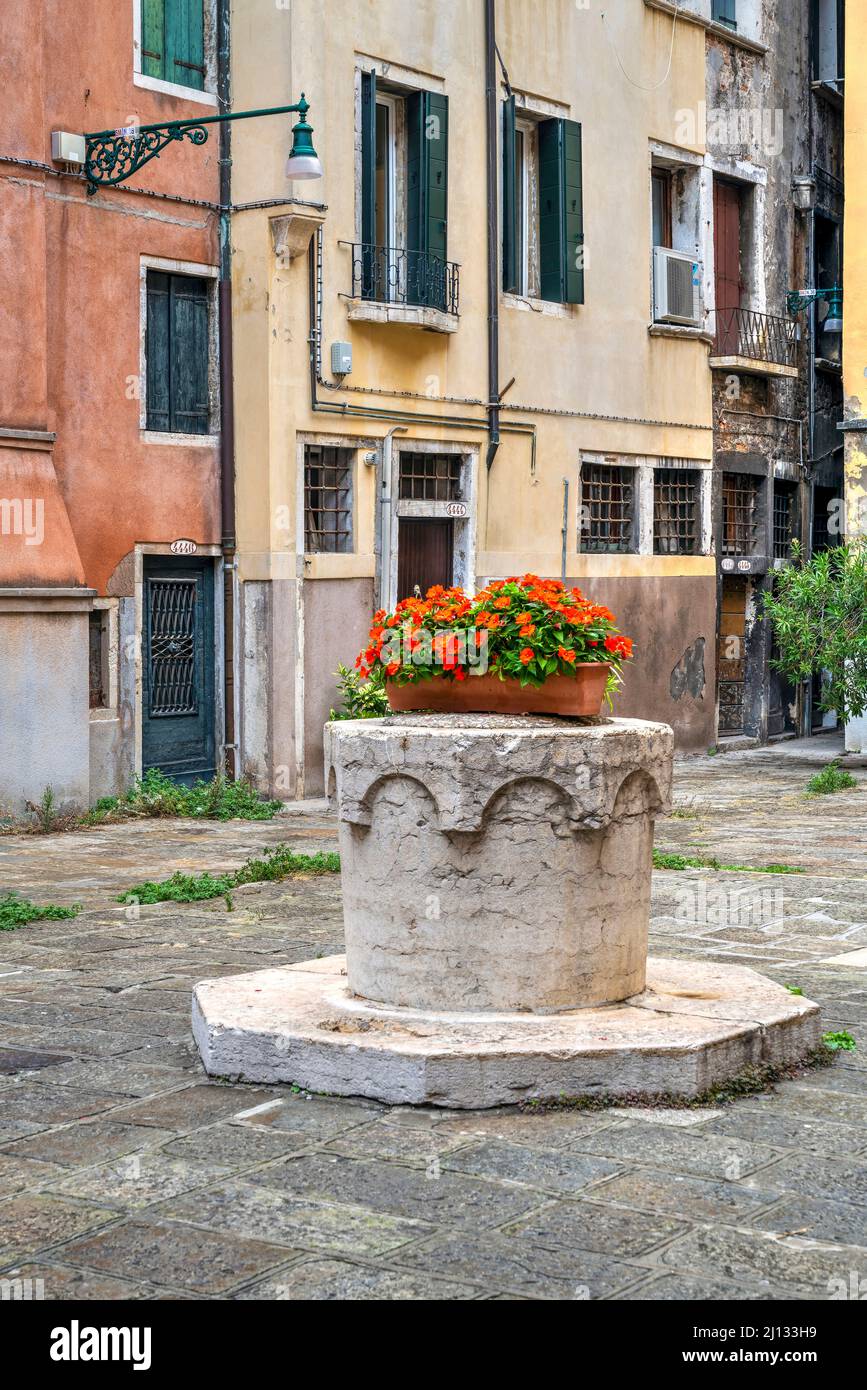 Vista panoramica su un tipico cortile con pozzo d'acqua in pietra (vera da pozzo), Venezia, Veneto, Italia Foto Stock