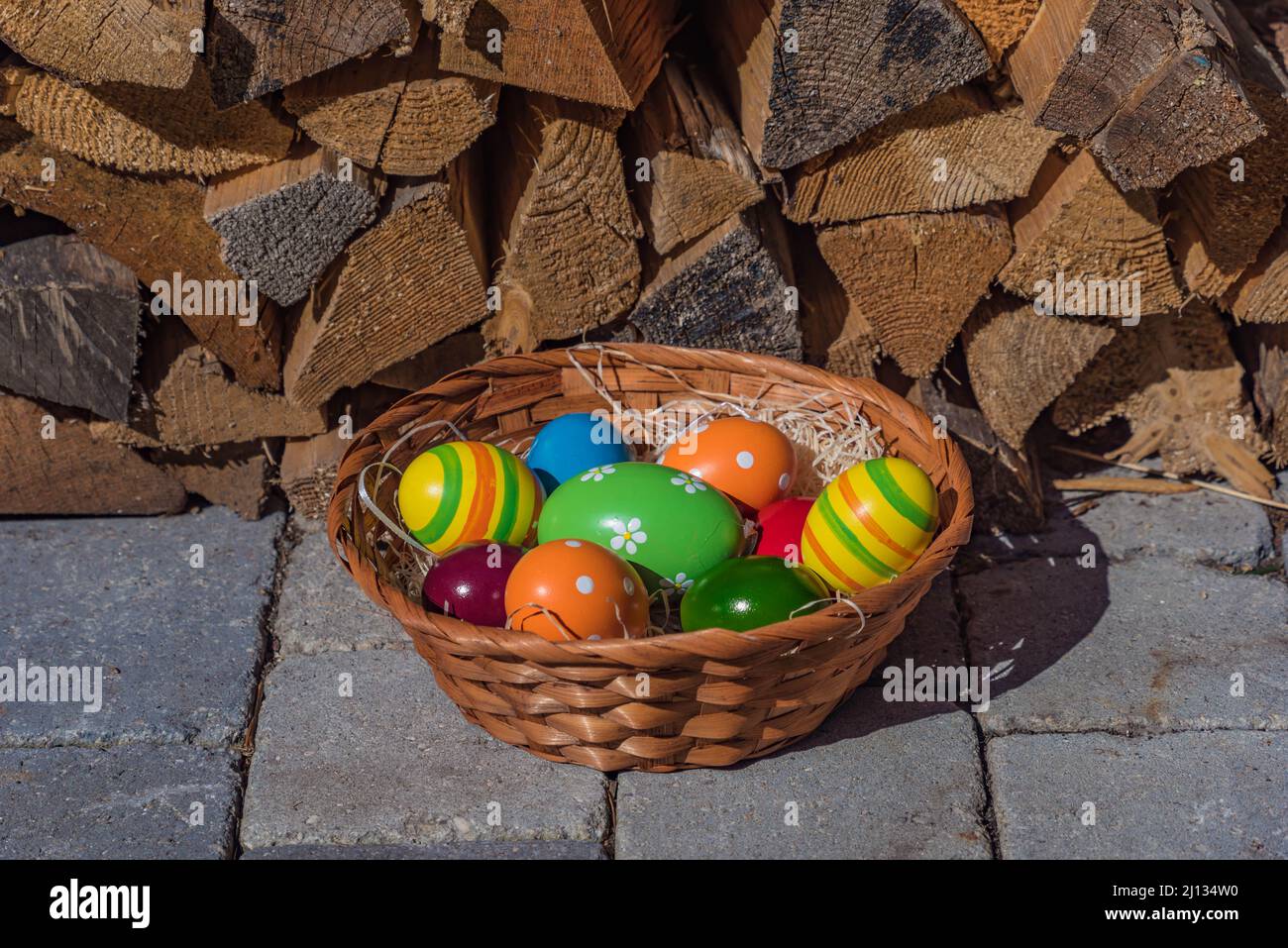 cestino intrecciato con uova di pasqua colorate in un nido di lana di legno, punto di legno in background, primo piano e isolato Foto Stock