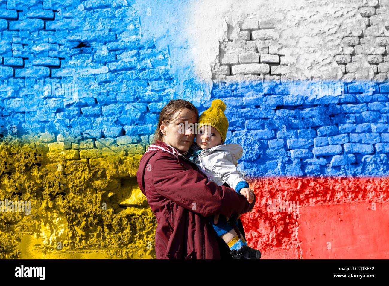 Una donna che tiene il suo figlio di fronte al concetto di tregua bandiera Ucraina e russa Foto Stock