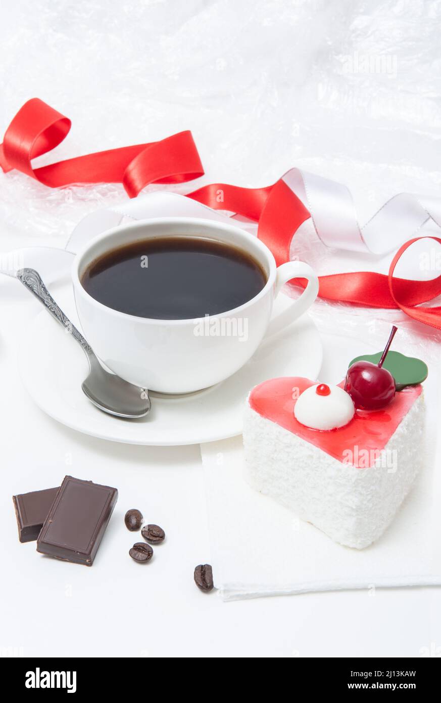 Tazza con caffè e torta in forma di cuore con ciliegie, cioccolato Foto Stock