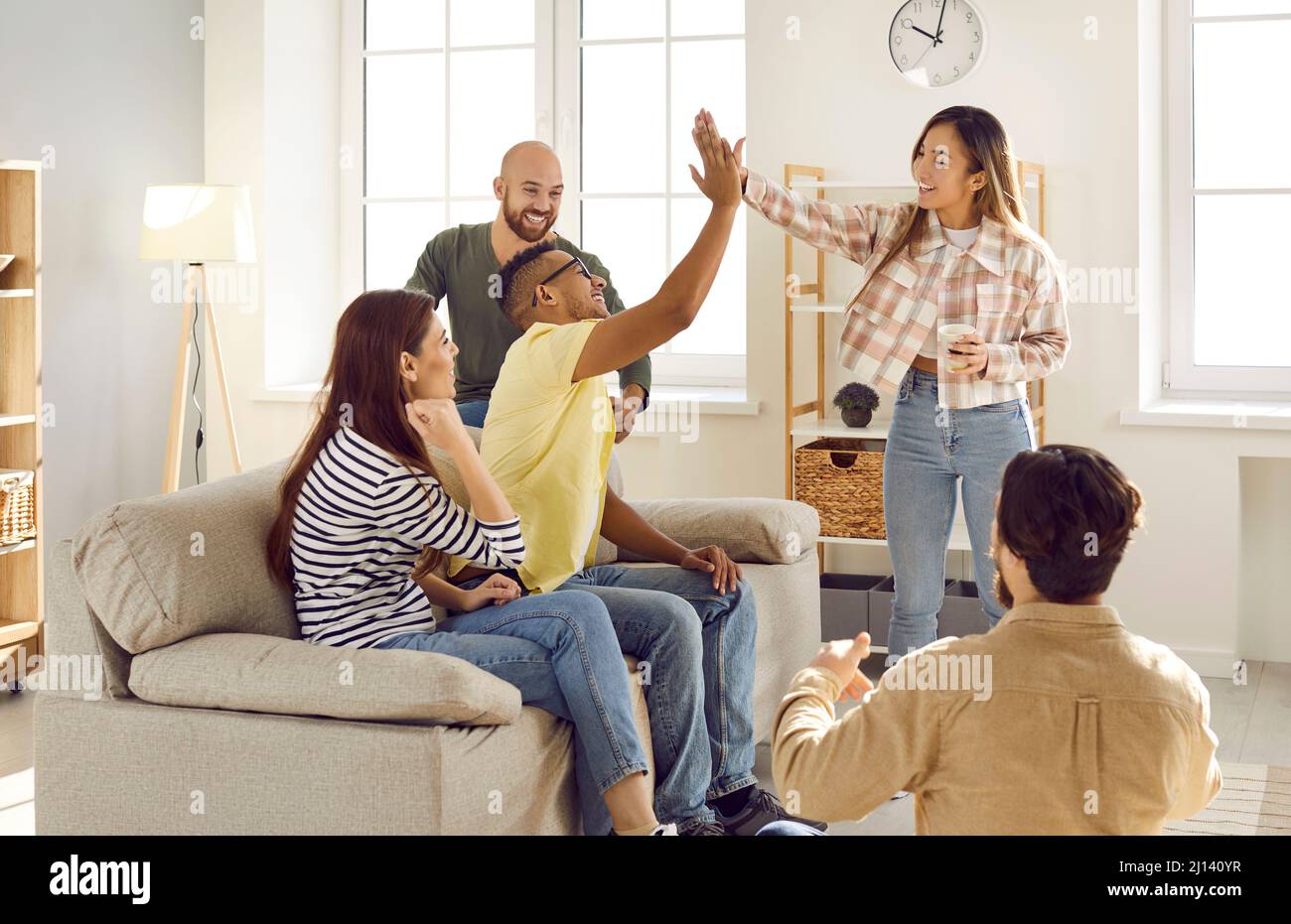 Sorridenti amici diversi dare alto cinque a gruppo di riunione Foto Stock