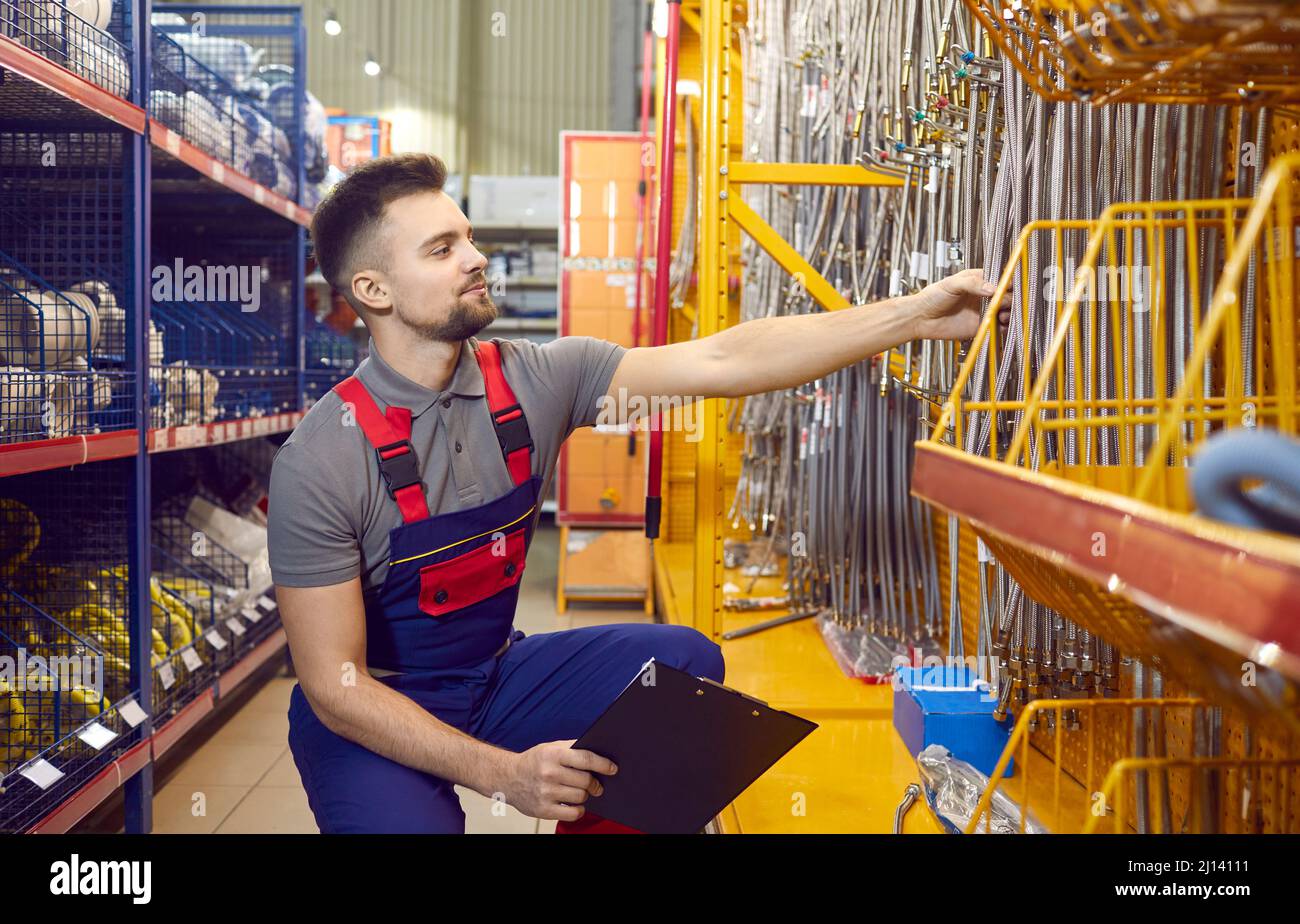 Venditore in un negozio di fai da te o centro commerciale che controlla i prodotti hardware in una delle navate Foto Stock