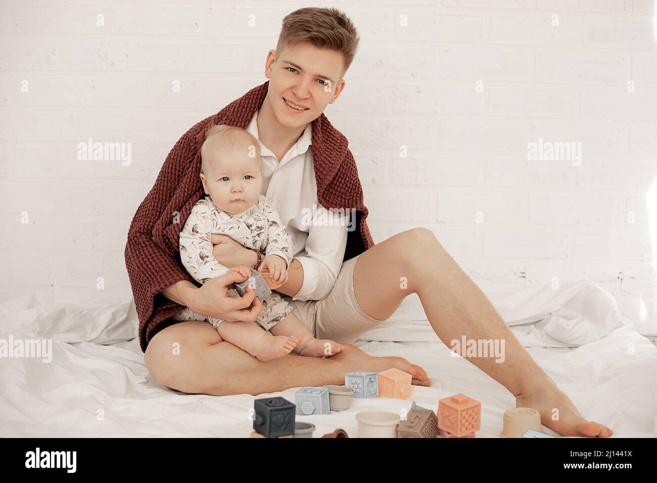 Ritratto di giovane uomo sorridente padre che tiene il bambino infante, giocando con i giocattoli, passando il tempo con il bambino, attività di vacanza Foto Stock