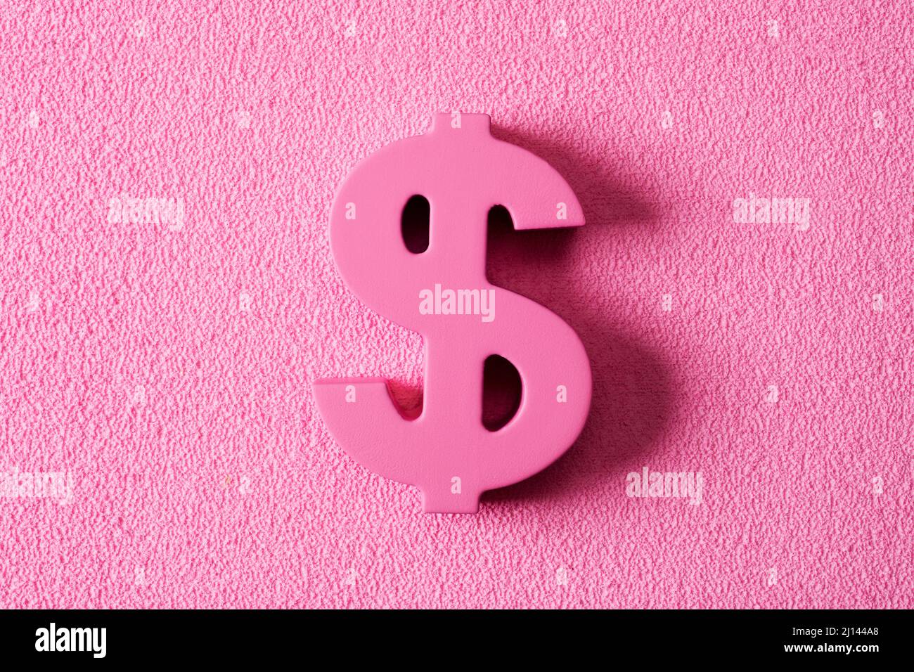 primo piano di un segno rosa del dollaro su uno sfondo rosa testurizzato, raffigurante il denaro rosa o concetti capitalismo rosa Foto Stock