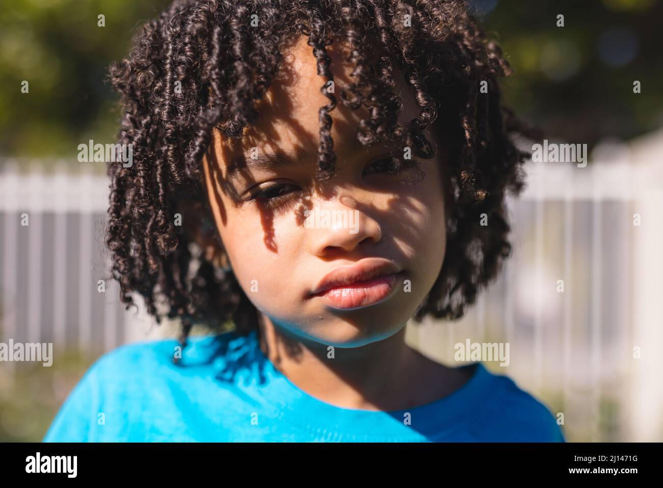 Primo piano ritratto di carino ispanico ragazzo con capelli ricci neri sul cortile in giornata di sole Foto Stock