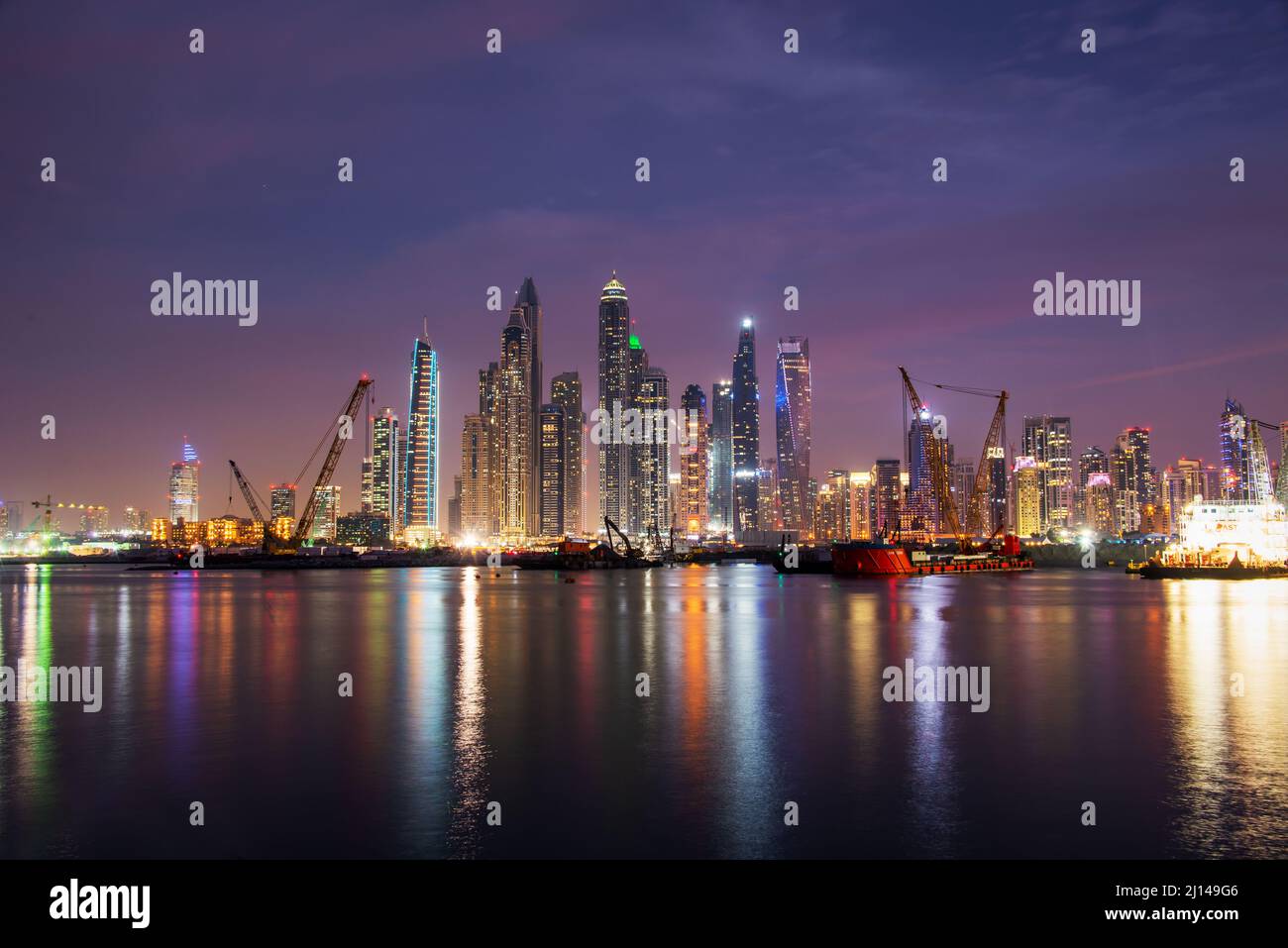 Marina di Dubai skyline notturno con acqua riflessioni, Emirati Arabi Uniti Foto Stock