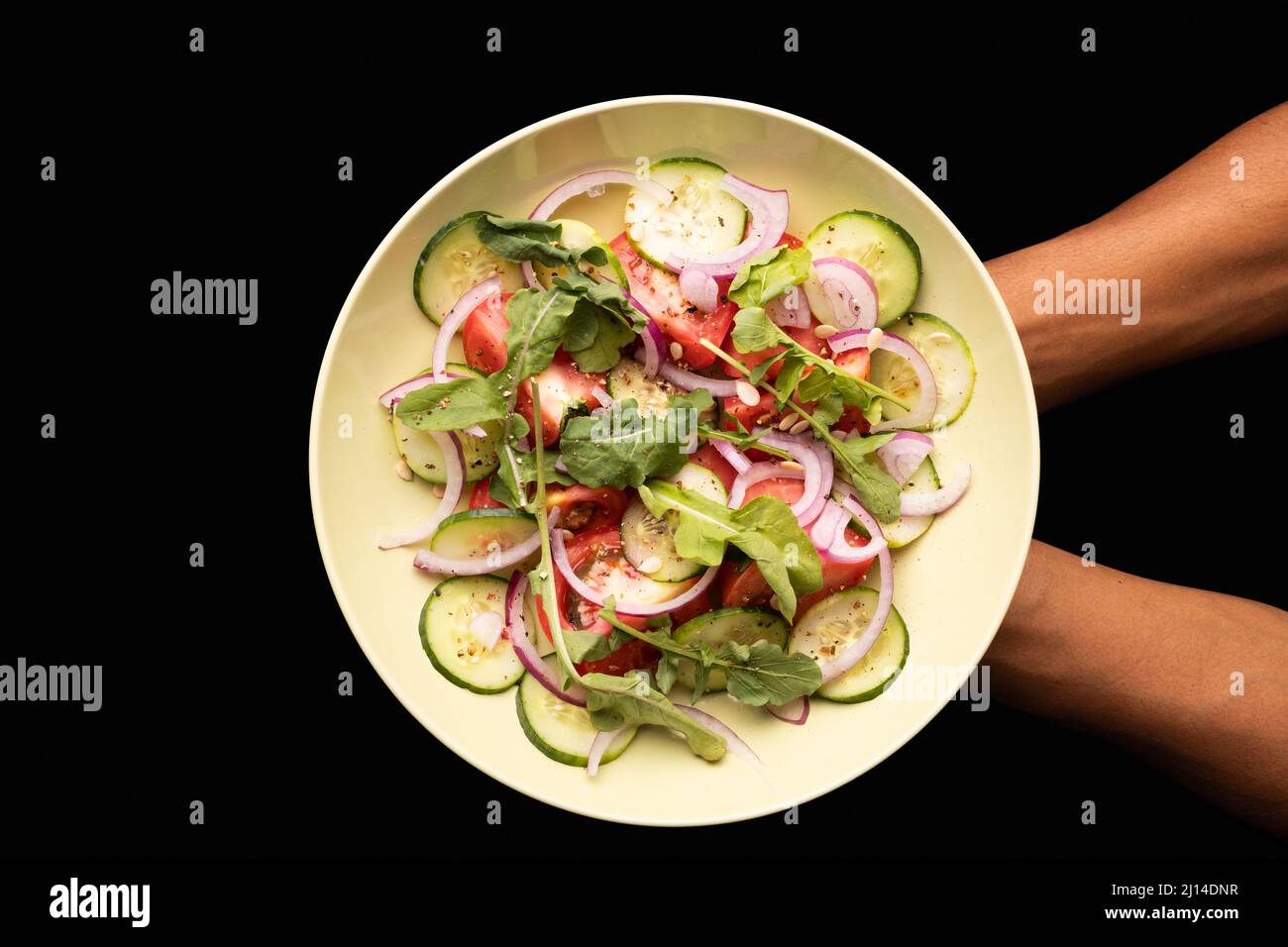 Direttamente sopra la vista del piatto di tenuta delle mani tagliate con insalata fresca su sfondo bianco Foto Stock