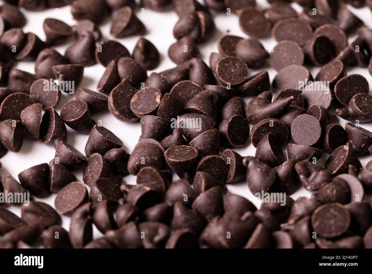 Primo piano con un'intera montatura di gocce di cioccolato fresco su sfondo bianco Foto Stock