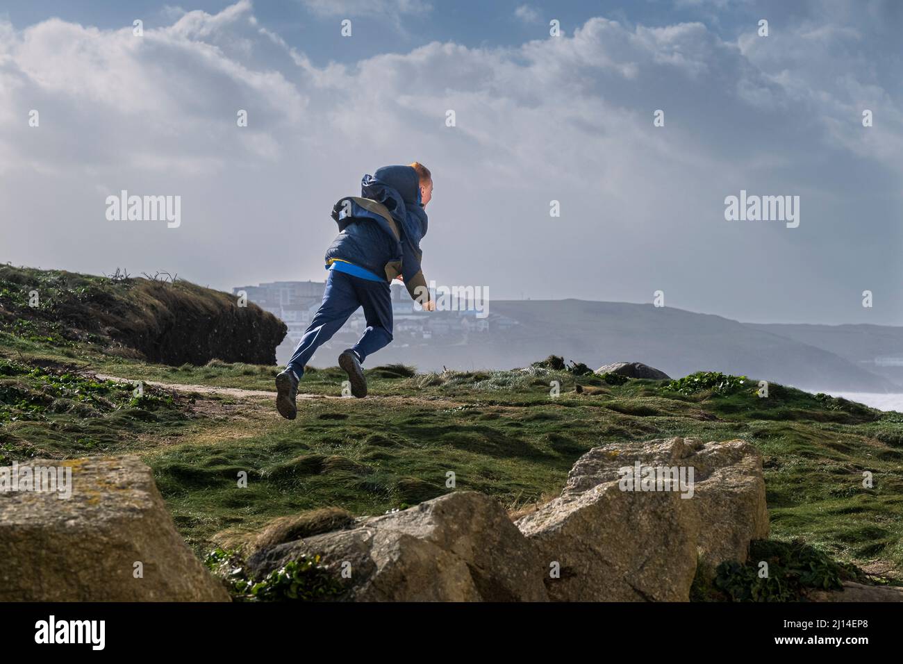 Un giovane ragazzo che si diverte a correre nel vento della tempesta, mentre Storm Eunice arriva in Cornovaglia nel Regno Unito. Foto Stock