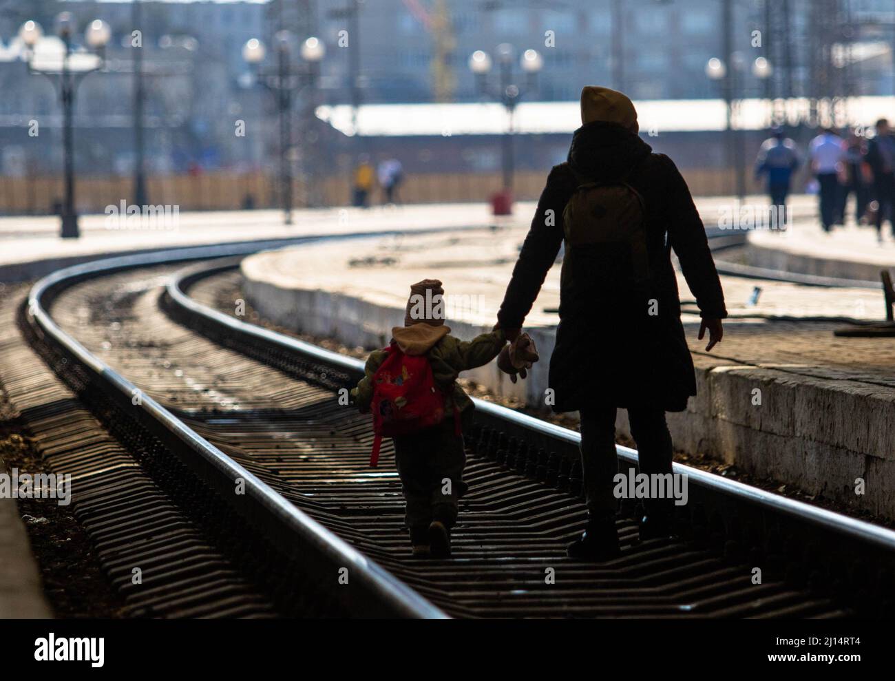 Una madre attraversa i binari del treno con il bambino dopo l'arrivo alla città di Lviv in treno. Mentre la guerra in Ucraina continua la gente fugge dalla violenza in treno che viene a Lviv o che viaggia verso la Polonia. Foto Stock