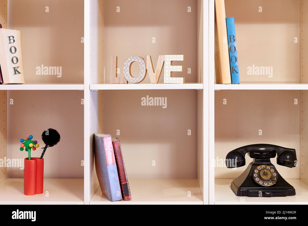 scaffale con libri vecchio telefono e lettere con la parola amore Foto Stock