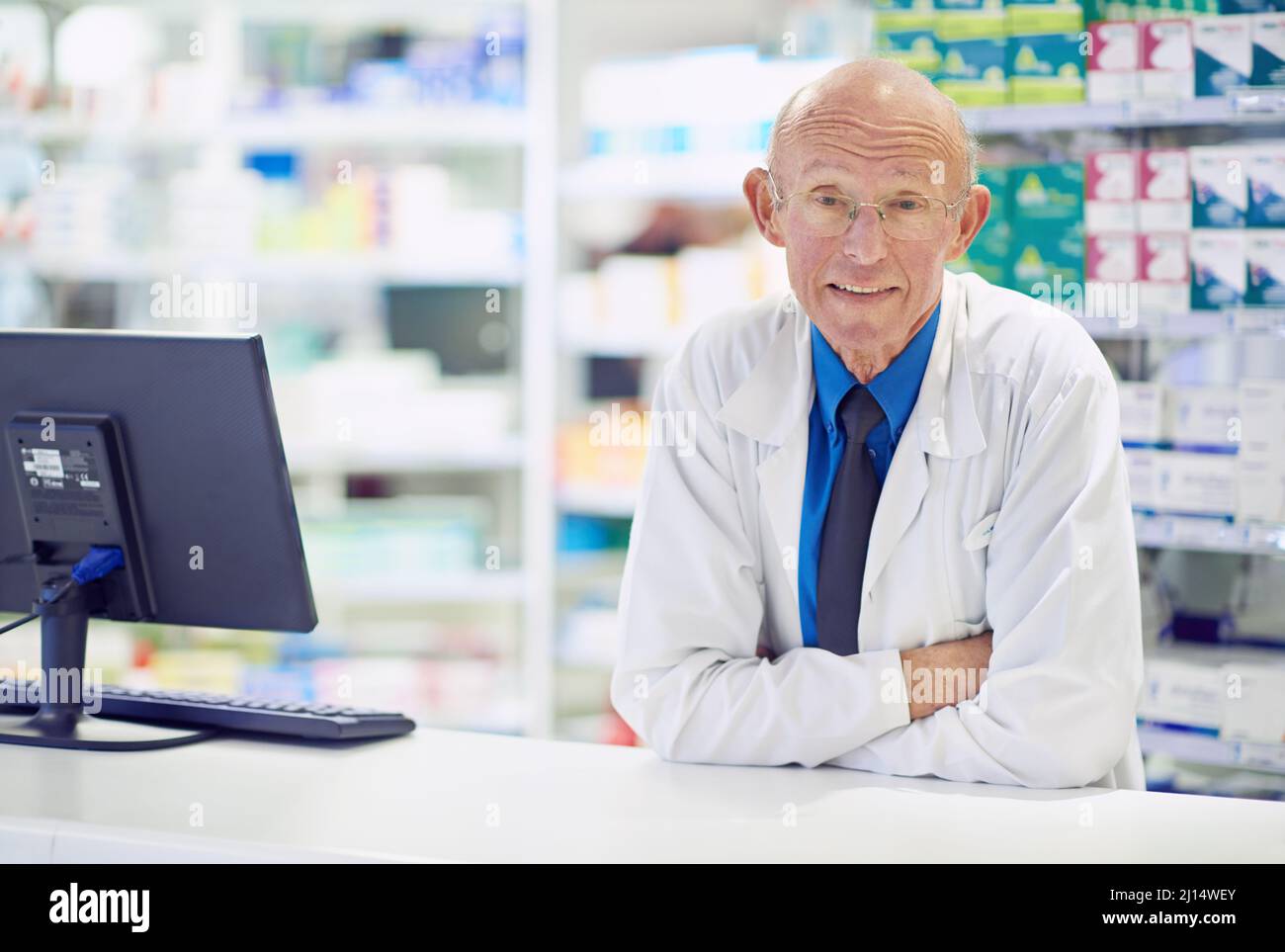 Ive visto un sacco di rimedi venire e andare.... Ritratto di un farmacista anziano che lavora al banco. Foto Stock